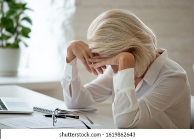 Middle-aged Businesswoman Took Off Eyeglasses Lowered Head Over Workplace Desk Feels Unhealthy Having Migraine Head Ache Caused By Workload, Dismissed Senior Employee Crying Age Discrimination Concept