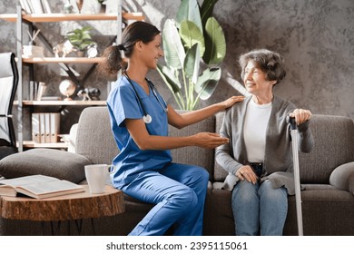 Middle-aged caregiver nurse doctor medical worker taking care of elderly senior patient, listening to complaints and diagnosis. Visiting lonely grandmother in hospice private clinic. - Shutterstock ID 2395115061