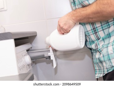 A middle-aged Caucasian man pours a laundry conditioner into the washing machine. - Shutterstock ID 2098649509