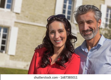 middle-aged couple in front of their house 