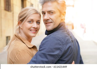 Middle-aged Couple Walking In Street Of Spanish Old Quarter