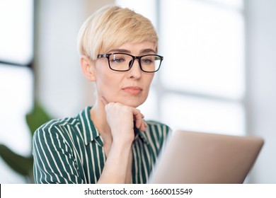 Middle-Aged Entrepreneur Lady Using Tablet Computer Reading Business News Online Sitting At Workplace Indoor. Selective Focus