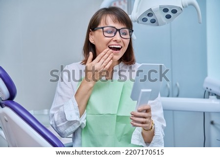 Middle-aged female in dental office looking in mirror