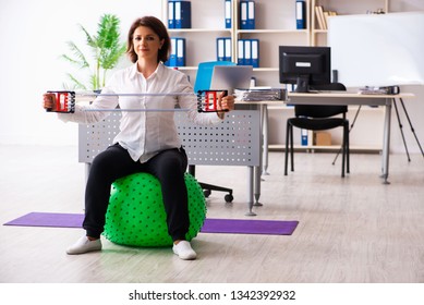 Middle-aged female employee doing exercises in the office  - Powered by Shutterstock