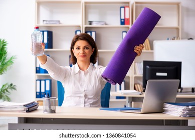 Middle-aged female employee doing exercises in the office  - Shutterstock ID 1360841054
