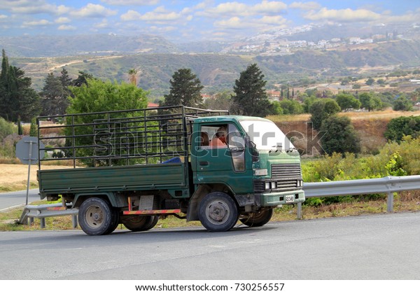 A\
middle-aged green lorry leaves for a turn in the background of the\
picturesque Cyprus Troodos Mountains and a blue sky with clouds.\
Concept: man and nature, unity and\
antithesis