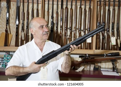 Middle-aged Gun Store Owner Looking At Weapon In Shop