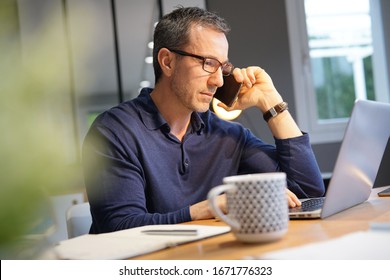 Middle-aged guy having hot drink, working on laptop - Powered by Shutterstock