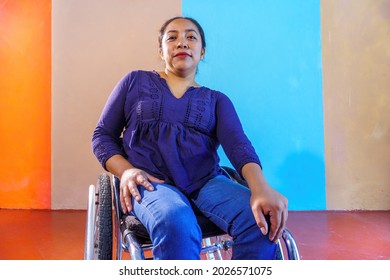 Middle-aged Hispanic woman with disabilities on a wheelchair against a colorful background - Powered by Shutterstock