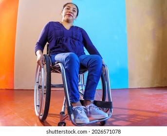 Middle-aged Hispanic woman with disabilities on a wheelchair against a colorful background