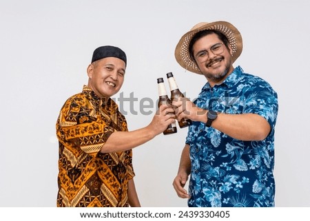 Middle-aged Indonesian man in batik and kopiah celebrates with a tourist in a Hawaiian shirt, toasting beers. White background.