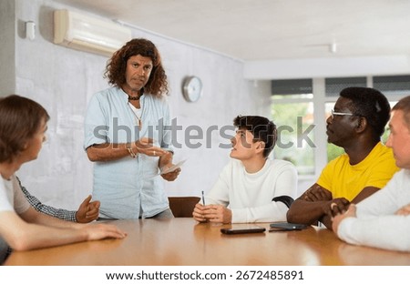 Middle-aged instructor conducting training with a group of young and middle-aged men sitting around the table