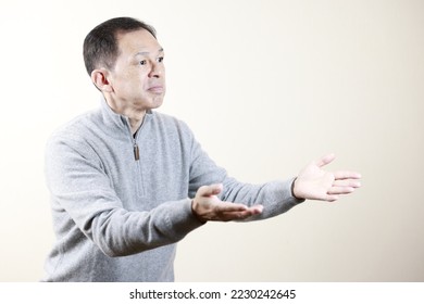 Middle-aged Japanese man in gray turtleneck wool sweater under white background. Concept image of Warm Biz, stability in daily life, and sustainable living. - Shutterstock ID 2230242645
