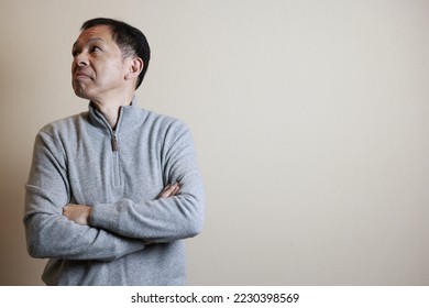 Middle-aged Japanese man in gray turtleneck wool sweater under white background. Concept image of Warm Biz, stability in daily life, and sustainable living. - Shutterstock ID 2230398569