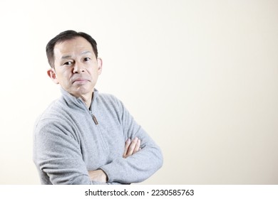 Middle-aged Japanese man in gray turtleneck wool sweater under white background. Concept image of Warm Biz, stability in daily life, and sustainable living. - Shutterstock ID 2230585763