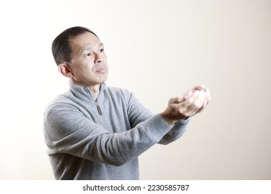 Middle-aged Japanese man in gray turtleneck wool sweater under white background. Concept image of Warm Biz, stability in daily life, and sustainable living. - Shutterstock ID 2230585787