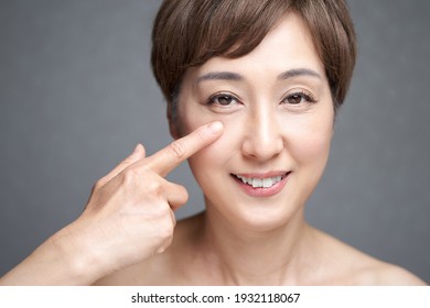 Middle-aged Japanese woman holding her eyes
