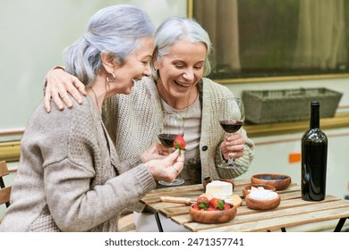 A middle-aged lesbian couple enjoys wine and laughter while camping in a green forest. - Powered by Shutterstock