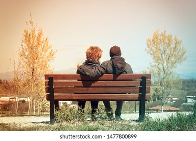middle-aged lovers date, back view of two people sitting on a bench in the park