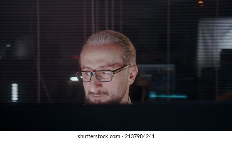 Middle-aged Male Office Employee Working Late In Dark Office. Modern Office Worker Working Overtime