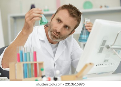 middle-aged male scientist examining liquid in glass flask - Powered by Shutterstock