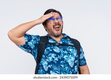 Middle-aged male tourist in a floral Hawaiian shirt looks stressed and facepalms, realizing he forgot something at home, isolated on white.