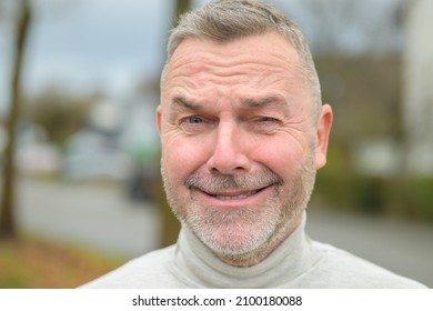 Middle-aged Man With Beard Standing Outdoors Winking At The Camera With A Wide Cheesy Grin