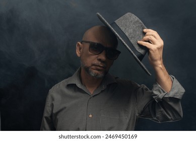 Middle-aged man with a beard wearing a hat and posing for the camera. Isolated on smoke-filled background. - Powered by Shutterstock