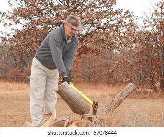 Middle-aged Man Chopping Fire Wood With An Ax On A Cold Late Fall Day