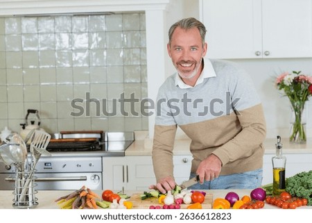 Middle-aged man chopping vegetables using chef knife on cutting board in home kitchen, copy space. Cooking, culinary, food prep, healthy lifestyle, rustic, vibrant, domestic