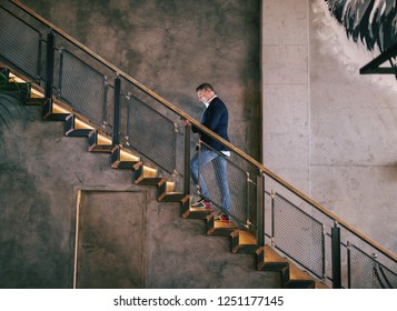 Middle-aged man dressed smart casual climbing the stairs and using tablet for video call. Full length. In ears earphones. - Powered by Shutterstock