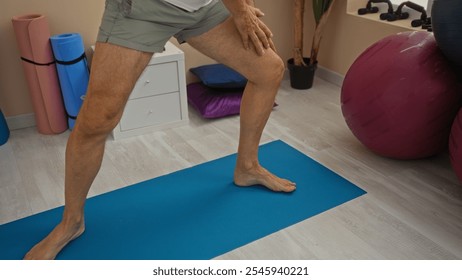 Middle-aged man exercising on yoga mat in wellness room with exercise balls and plants showcasing healthy lifestyle indoors. - Powered by Shutterstock