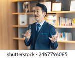 A middle-aged man giving a speech with a microphone in the lobby