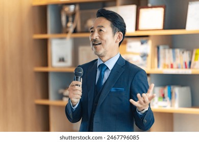 A middle-aged man giving a speech with a microphone in the lobby - Powered by Shutterstock