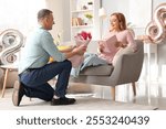 Middle-aged man greeting his wife with bouquet of flowers at home. International Women