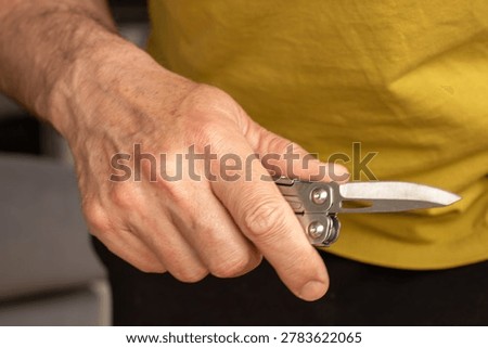 Middle-aged man hand holding sharp pocketknife, concept of violence, assault, murder, force, abuse, and domestic violence.