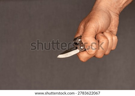 Middle-aged man hand holding sharp pocketknife, concept of violence, assault, murder, force, abuse, and domestic violence.