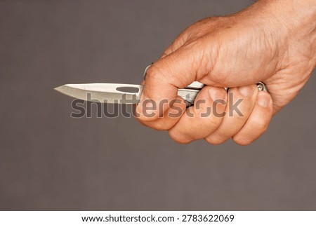 Middle-aged man hand holding sharp pocketknife, concept of violence, assault, murder, force, abuse, and domestic violence.