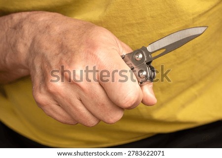 Middle-aged man hand holding sharp pocketknife, concept of violence, assault, murder, force, abuse, and domestic violence.