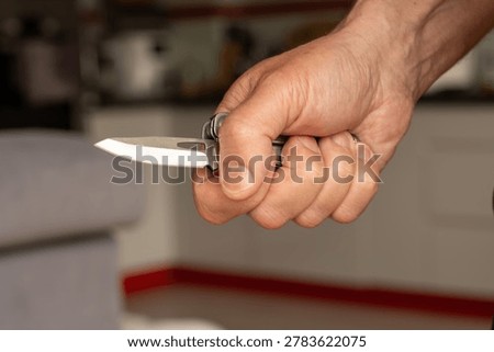 Middle-aged man hand holding sharp pocketknife, concept of violence, assault, murder, force, abuse, and domestic violence.