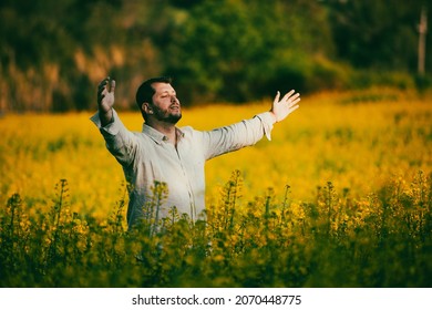 Middle-aged Man With His Arms Open Facing The Sun, In An Attitude Of Gratitude In A Field Of Wild Flowers. Overcoming Phobias And Accepting Fears.