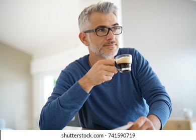 Middle-aged man at home drinking coffee and reading newspaper - Powered by Shutterstock