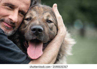 A middle-aged man hugs a dog on a walk. Close-up. - Powered by Shutterstock