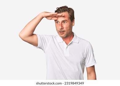 A middle-aged man isolated looking far away keeping hand on forehead. - Shutterstock ID 2319849349
