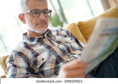 Middle-aged man in kitchen reading newspaper - Powered by Shutterstock