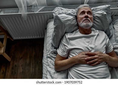 middle-aged man lying down in bed on pillow, having insomnia sleeping disorder. alone at home