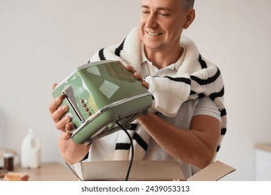 Middle-aged man with new toaster in kitchen