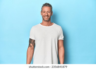 Middle-aged man posing on blue studio backdrop - Powered by Shutterstock