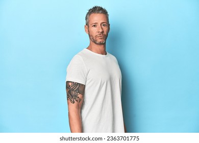 Middle-aged man posing on blue studio backdrop - Powered by Shutterstock