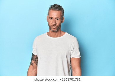 Middle-aged man posing on blue studio backdrop